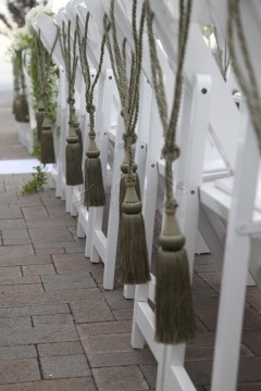 Decorative brooms hanging on white wooden racks outdoors.