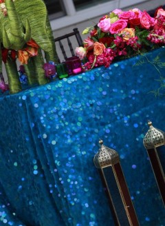 Decorative table with sequined blue cloth, flowers, and lanterns.