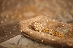 Elegant gold and pearl jewelry on delicate beige fabric.