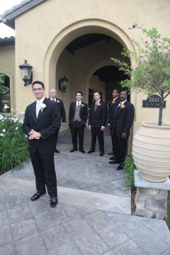 Groom and groomsmen posing outside an elegant building.