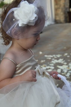 A young girl in a white dress and headpiece holding a basket of flower petals.