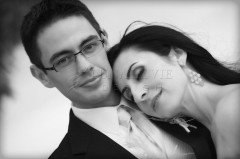 A couple in formal attire posing closely, the woman resting her head on the man's shoulder.