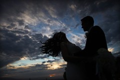 Silhouette of a couple embracing at sunset with dramatic clouds.
