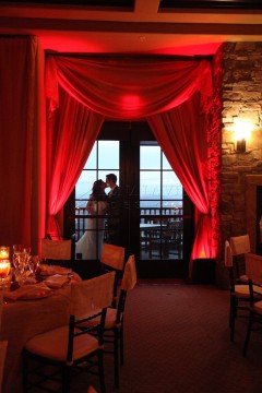 Couple sharing a romantic moment in a warmly lit room with red curtains.