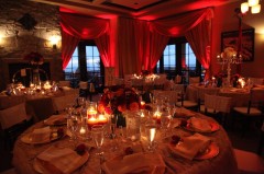 Elegant dining setup with warm red lighting and candlelit tables.