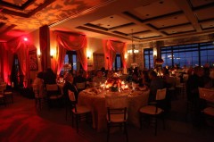 Elegant dinner event with warm lighting and guests seated at round tables.