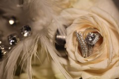 Elegant wedding rings nestled in a cream rose with soft feathers.