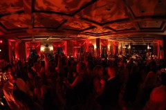 Crowded dance floor with vibrant red lighting and energetic partygoers.